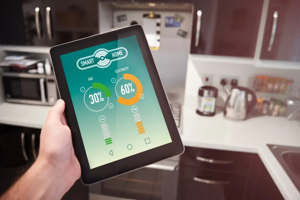 imagen de una tablet en la mano de una persona y de fondo sale una cosina con utiencilios